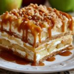 delicious layered dessert Caramel Apple Eclair Cake , whipped cream, apple slices, and caramel sauce drizzled on top. The dessert is garnished with crumbled bits on top, likely from the graham crackers or other ingredients
