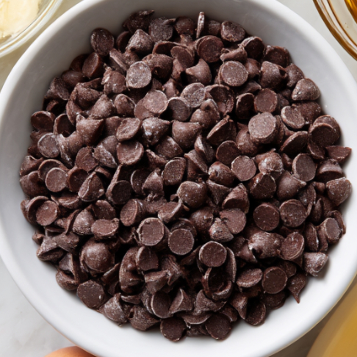 bowl filled with chocolate chips, possibly ready to be melted or mixed into a recipe. The chips are small, uniform, and have a deep, rich color.