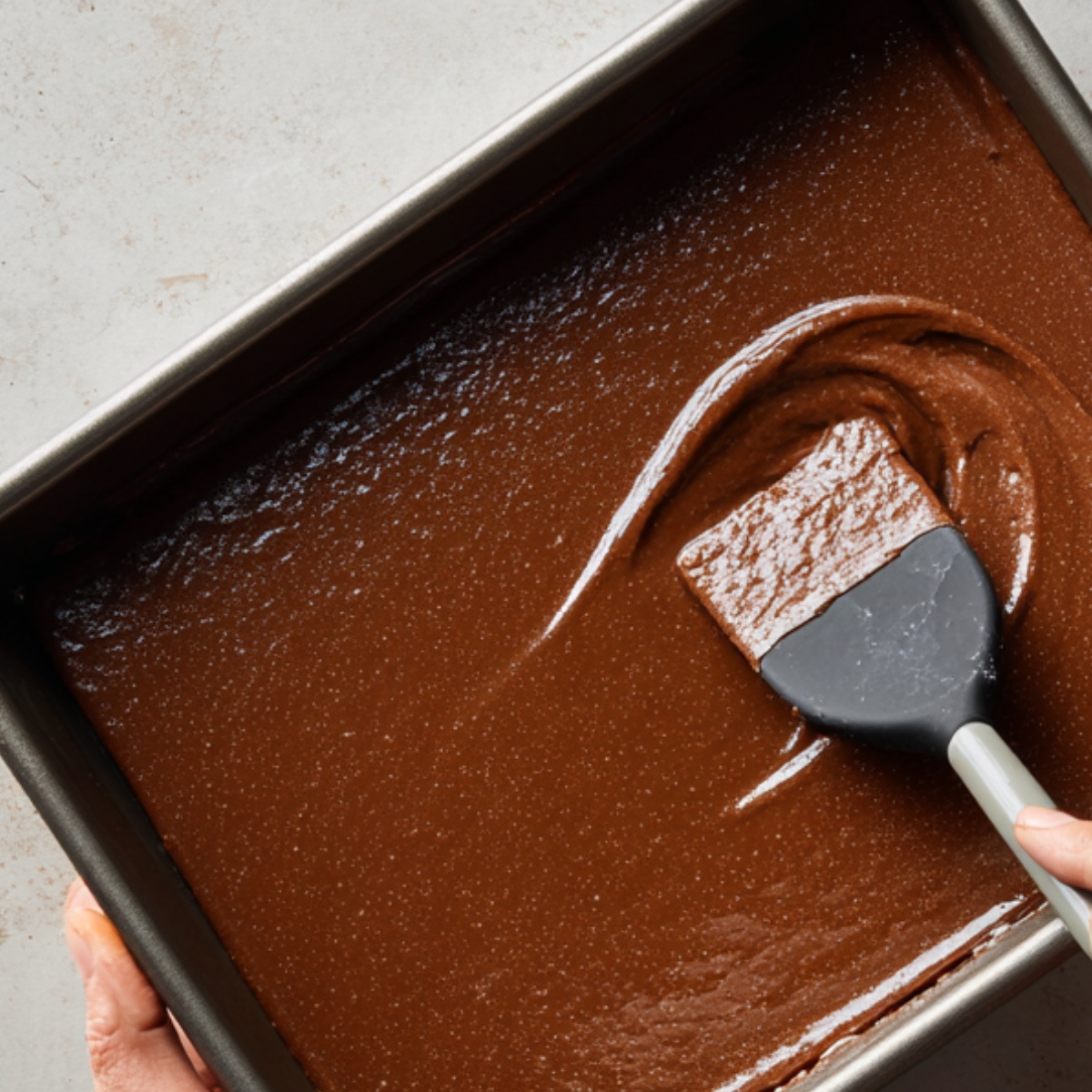 neatly arranged grid of chocolate fudge squares on a wooden board. The fudge pieces are perfectly cut, with a glossy finish and uniform size, suggesting a homemade treat.