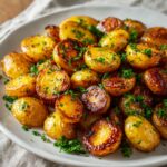 Crispy roasted petite gold potatoes with parsley on a white plate, golden brown and glistening with butter and olive oil.