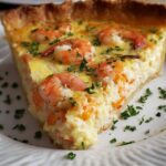 A slice ofFlorida shrimp pie quiche with parsley garnish, showing a golden crust and a creamy filling with shrimp on top.