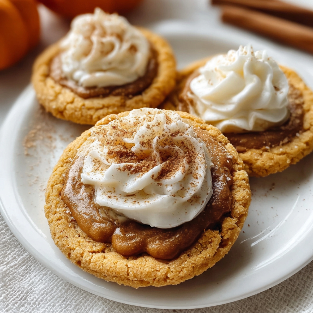 “pumpkin pie cookie topped with whipped cream and sprinkled with cinnamon on a white plate — cozy fall dessert.”