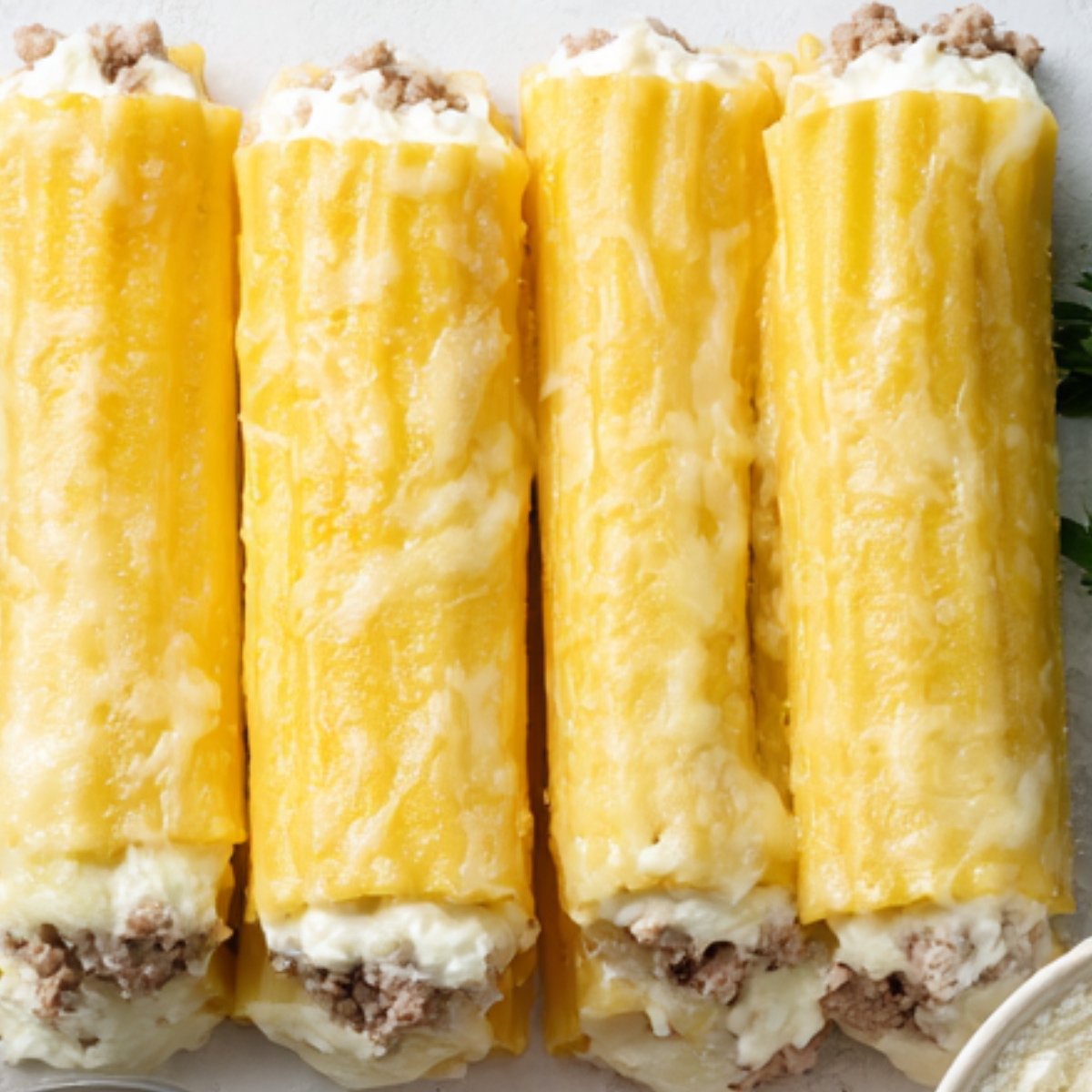 Unbaked manicotti tubes filled with ricotta cheese and ground beef mixture, ready for the oven.”
