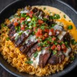 A bowl of steak and queso rice and rice topped with creamy cheese sauce, pico de gallo, and fresh cilantro.