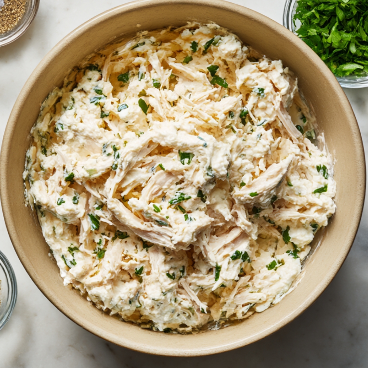 Chicken and cheese filling mixture in a bowl made with shredded chicken, ricotta, Parmesan, and chopped parsley.