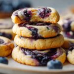 A stack of golden blueberry cheesecake swirl cookies with swirls of blueberry filling, showing their soft texture and rich flavor.