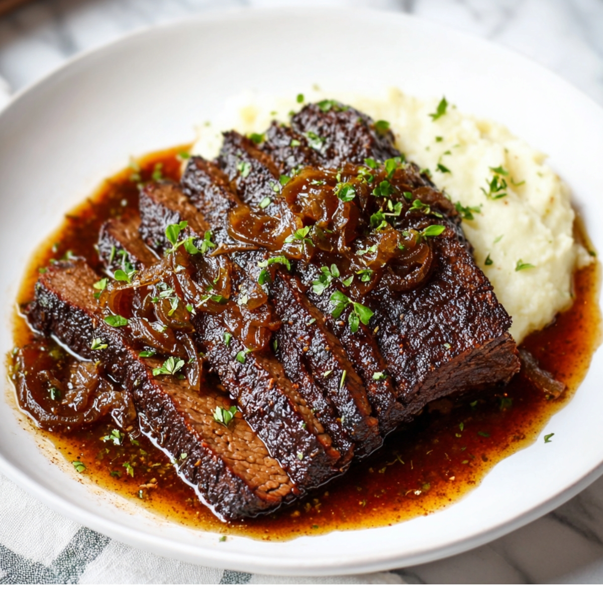Juicy sliced beef Red Wine Braised Brisket topped with caramelized onions and fresh herbs, served over creamy mashed potatoes with gravy.