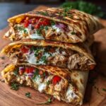 “Stacked halves of grilled Chicken Pitas filled with shredded chicken, diced tomatoes, red onions, herbs, and creamy ranch sauce on a wooden board.”
