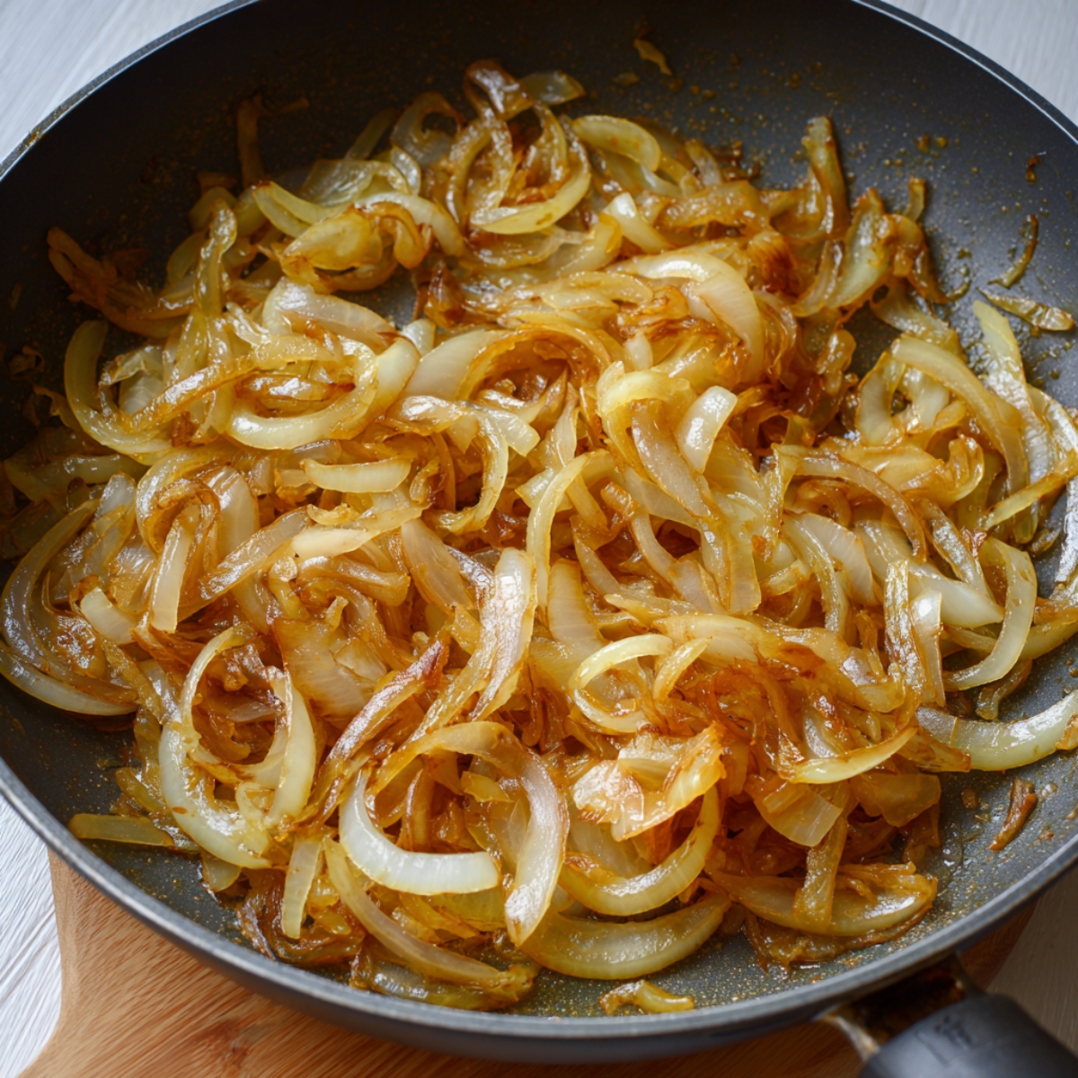 “A skillet of caramelized onions cooked to golden brown perfection, glistening with butter and ready to be added to the casserole.”