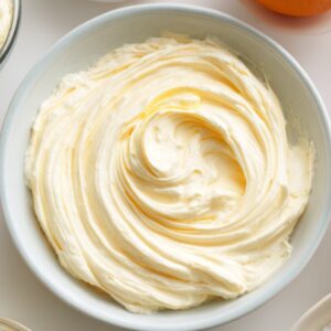 Smooth cream cheese mixture whipped to a creamy texture in a white bowl, ready to be used for brownie or dessert swirl filling.
