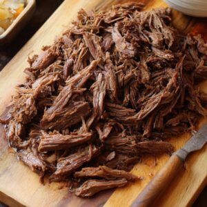 Shredded beef on a cutting board..Crock Pot French Dip Sandwiches