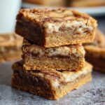 “Stack of chewy cinnamon sugar blondies with a crackly cinnamon top and fudgy center, showing layers of golden brown texture.”