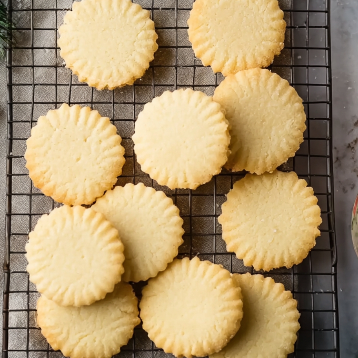 Rolled-out shortbread dough with round cookie shapes being cut using a cookie cutter, surrounded by flour and measuring cups