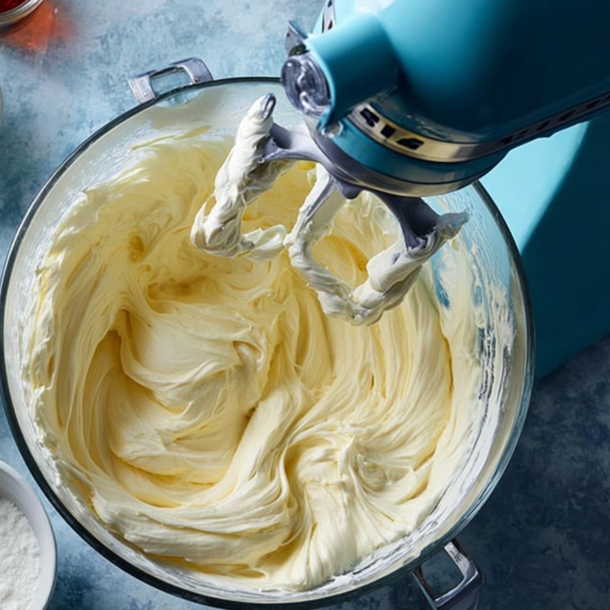 Stand mixer whipping smooth cream cheese filling in a bowl.