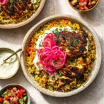 One Pan Shawarma Chicken and Rice with yogurt sauce and pickled onions.”
