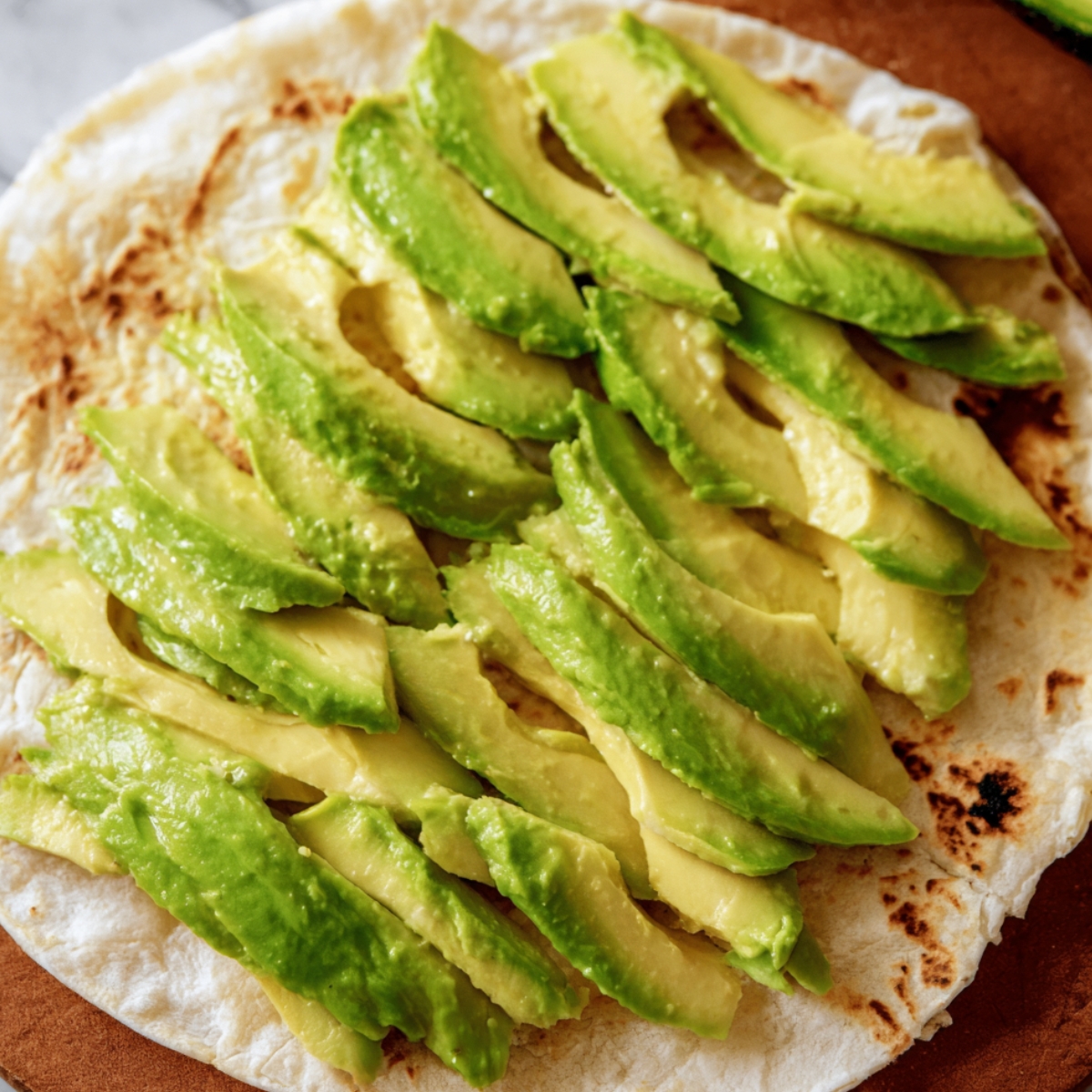 Sliced avocado arranged on a warm tortilla.