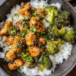 The image shows a delicious plate of jalapeño chicken recipe served with white rice and roasted broccoli, garnished with sesame seeds, cilantro, and sliced jalapeños.