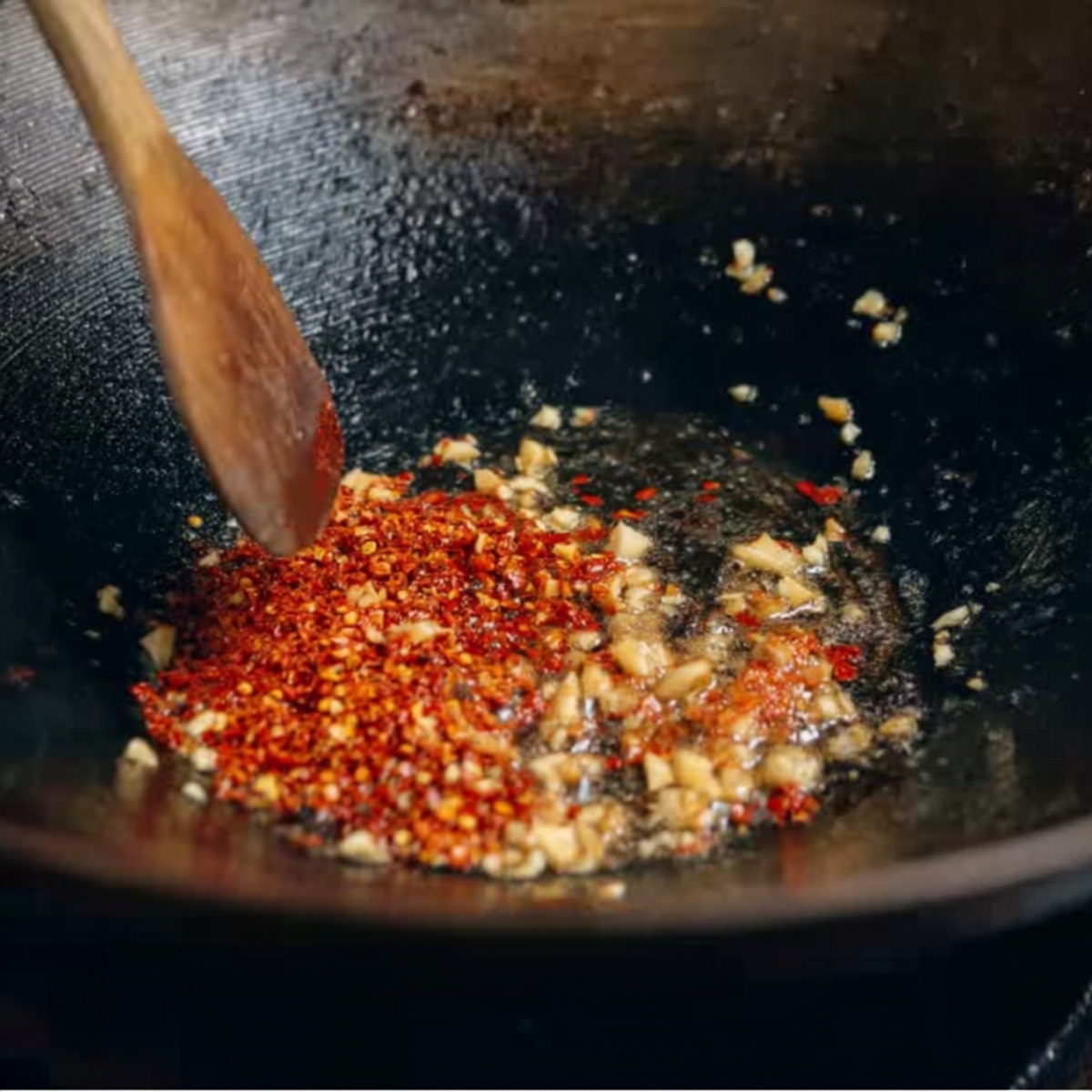 Chili flakes and garlic sizzling in hot oil.