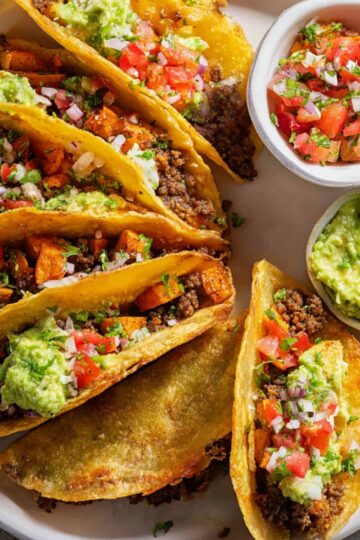 Crispy Ground Beef Tacos topped with guacamole and pico de gallo