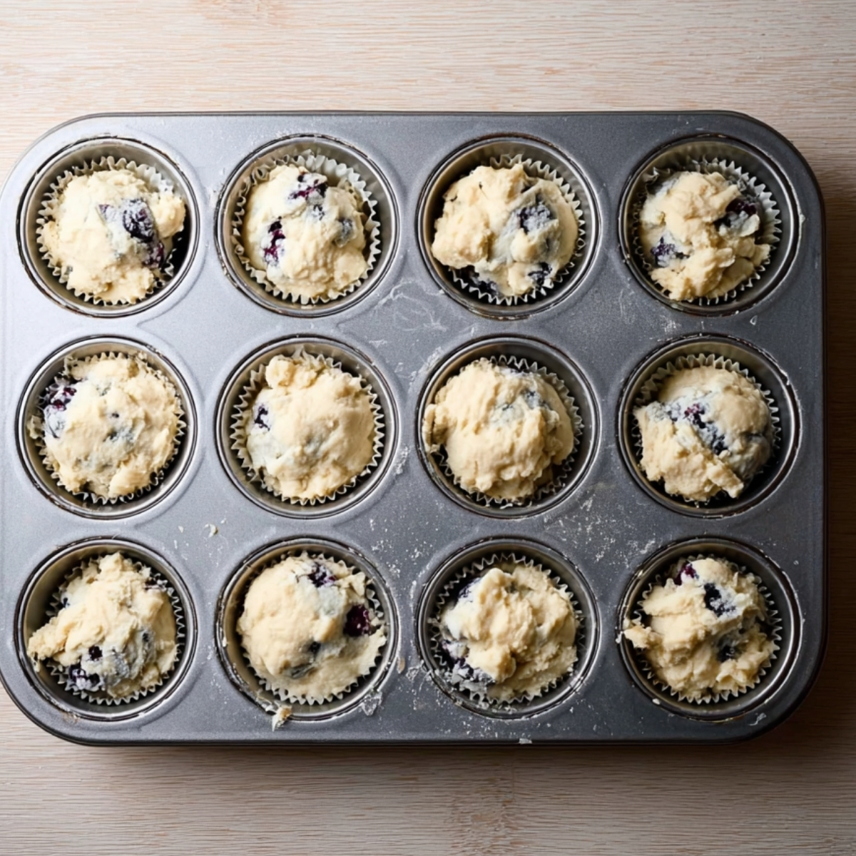 Muffin tin filled with blueberry muffin batter