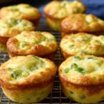 The image shows Fluffy Cottage Cheese Egg Muffins with visible green onions, cooling on a wire rack.