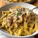 A creamy Garlic Parmesan Chicken and Pasta slices and fresh herbs.