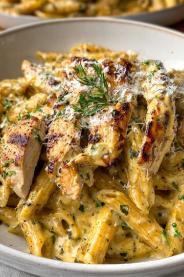 A creamy Garlic Parmesan Chicken and Pasta slices and fresh herbs.