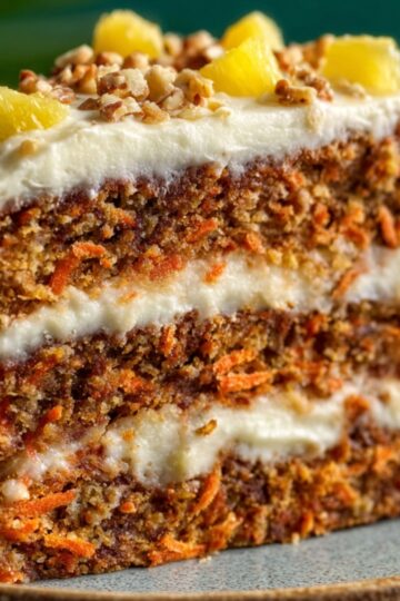 Slice of Hawaiian carrot pineapple cake with cream cheese frosting and orange zest