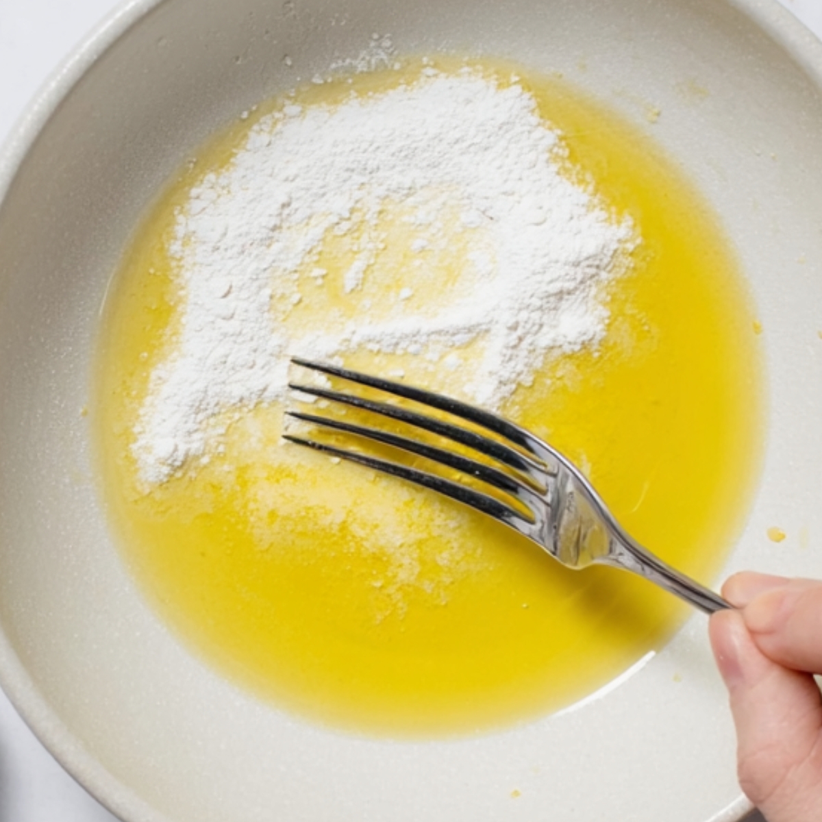 Butter and flour in a bowl, being mixed together with a fork to make a soaking syrup.