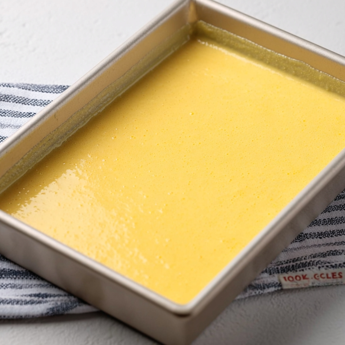 A yellow batter poured into a rectangular baking pan, ready to be baked.