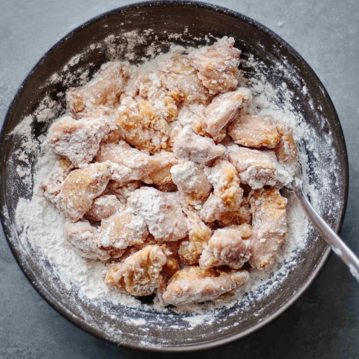 Chicken pieces coated in flour, ready to be cooked.