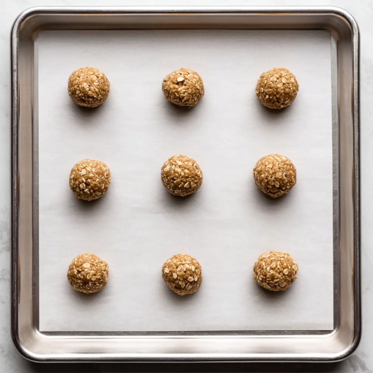 Energy balls spaced on a parchment-lined baking sheet.