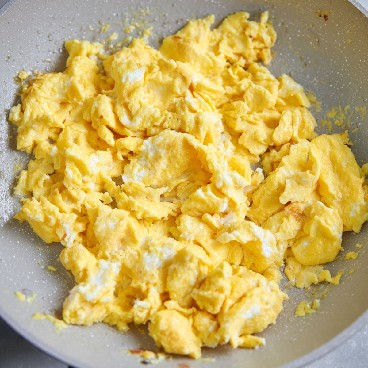 Soft scrambled eggs cooking in a skillet.