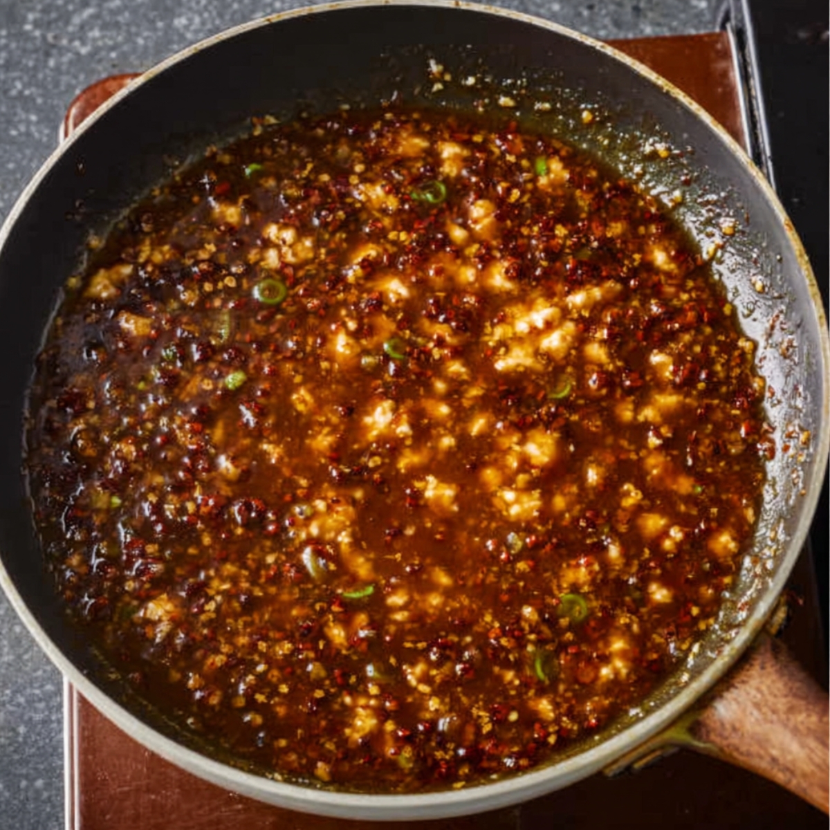 A flavorful stir-fry sauce simmering with chili flakes and green onions.
