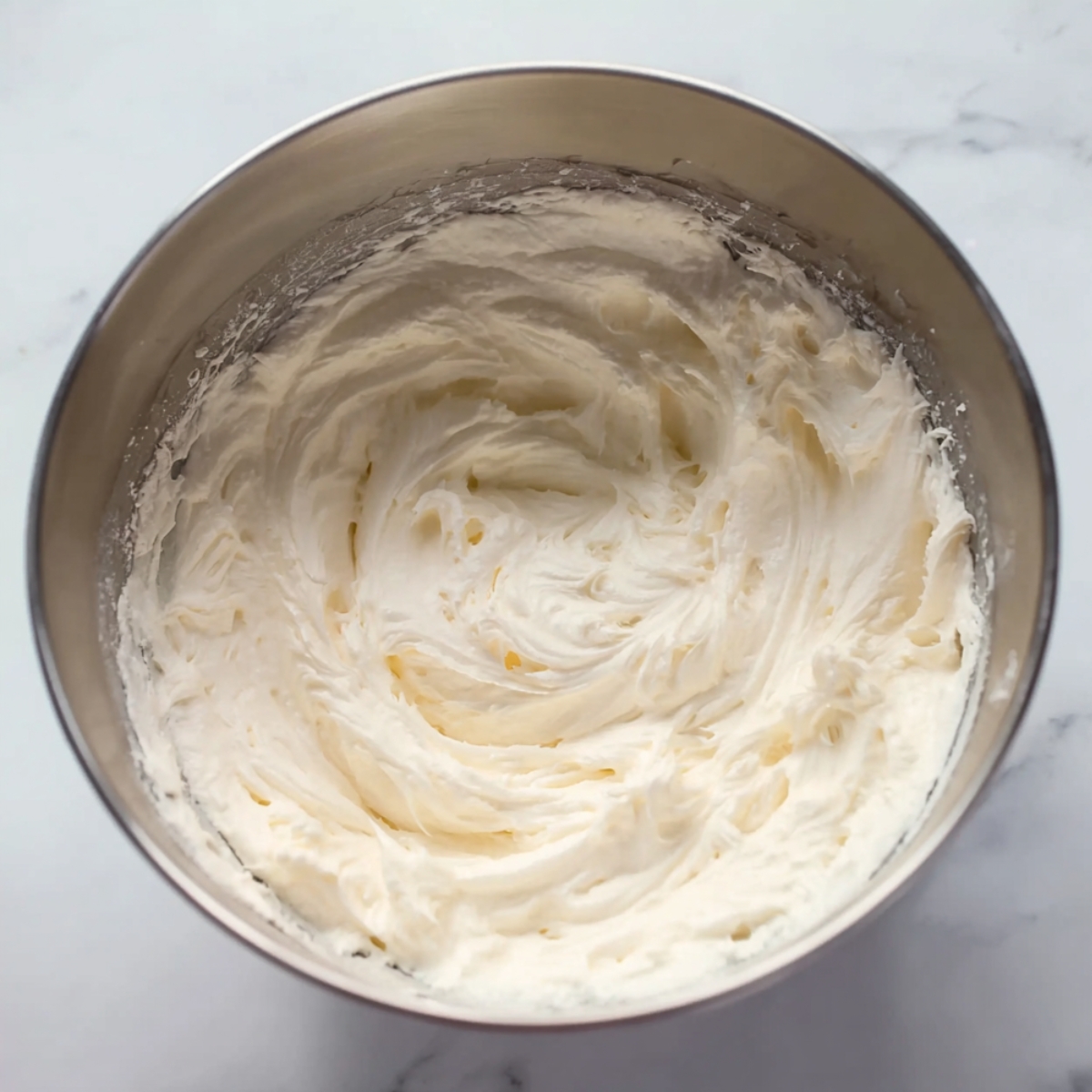 A fluffy and smooth whipped cream mixture in a mixing bowl.