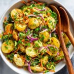 Turkish patates salatasi with herbs, red onion, and carrots in a bowl.