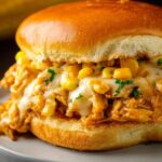 Close-up of a Cajun Chicken Sloppy Joes on a golden hamburger bun, filled with creamy cheesy chicken, corn, and garnished with chopped parsley.